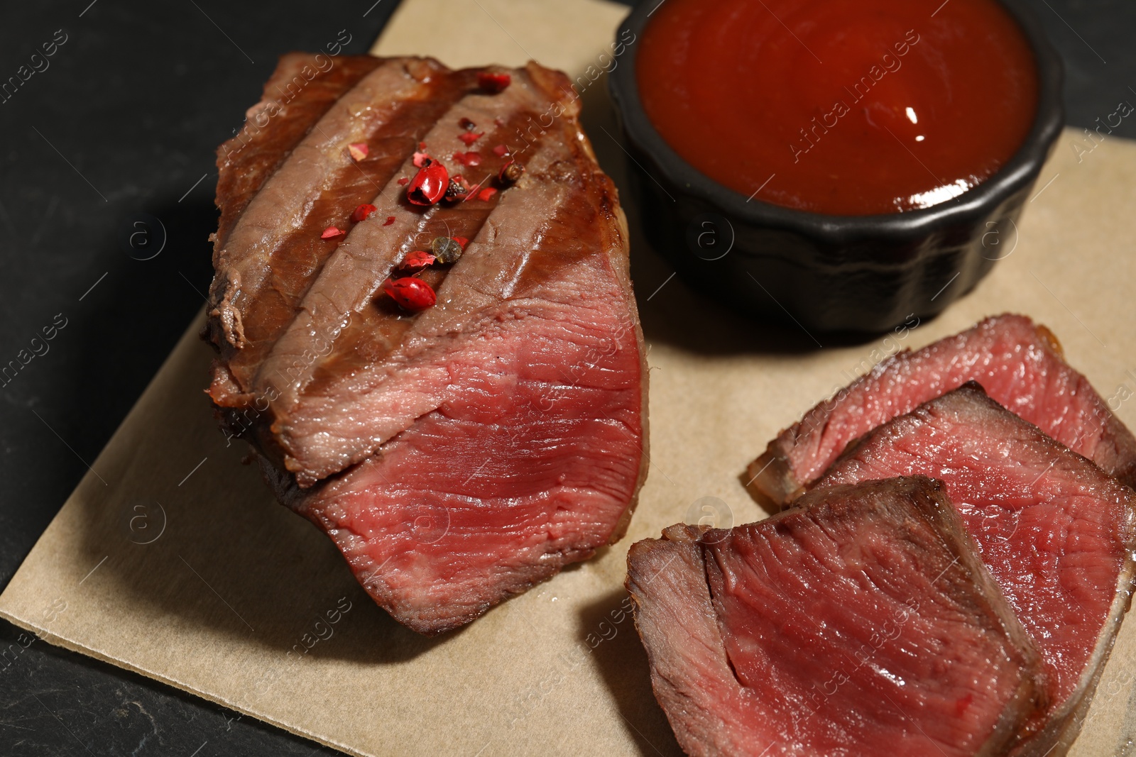 Photo of Delicious grilled beef steak with spices and tomato sauce on table, closeup