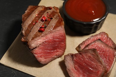 Delicious grilled beef steak with spices and tomato sauce on table, closeup