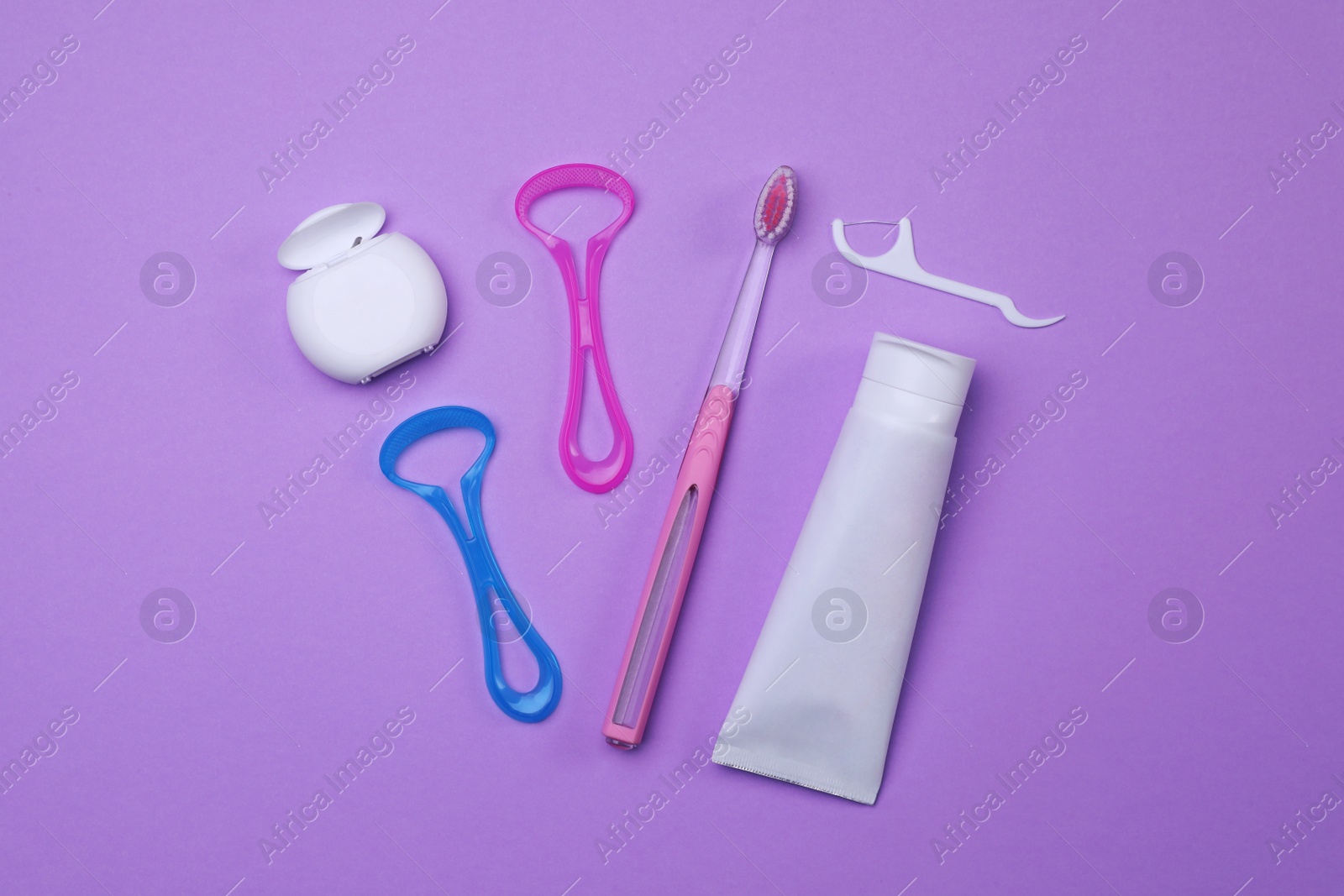 Photo of Flat lay composition with tongue cleaners and teeth care products on violet background