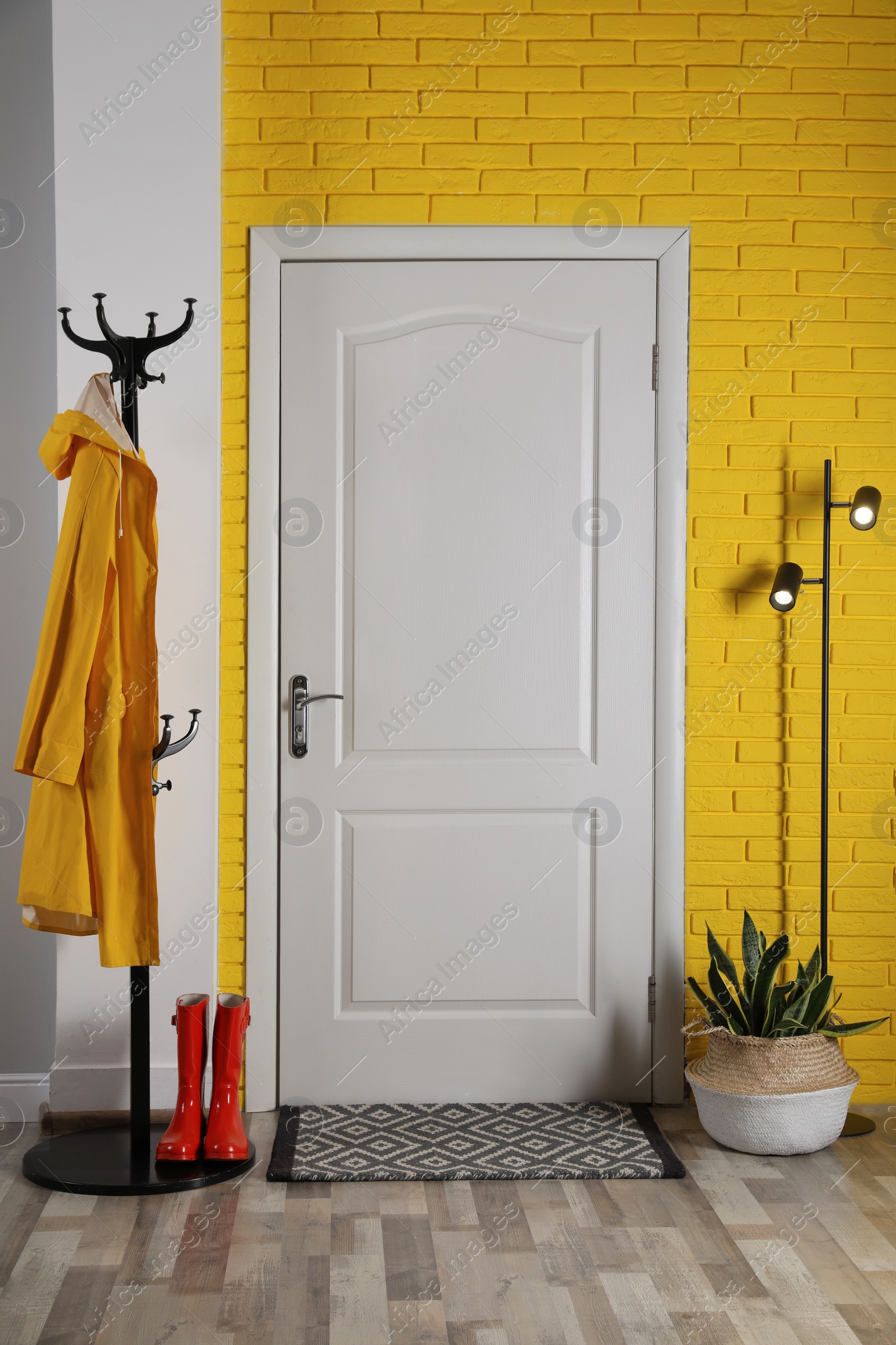 Photo of Hallway interior with beautiful houseplant, hanger stand and door mat on floor near entrance