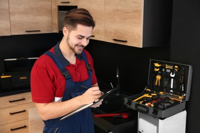 Photo of Male plumber with clipboard in kitchen. Repair service