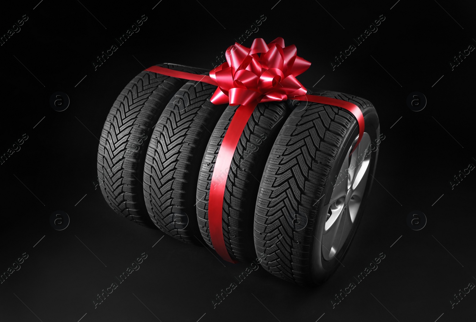 Photo of Gift set of wheels with winter tires on black background