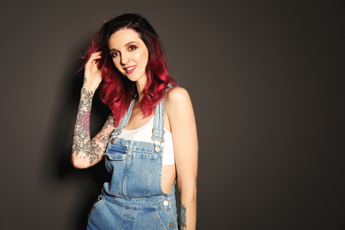 Photo of Beautiful woman with tattoos on arms against black background. Space for text