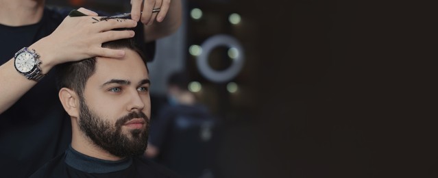 Image of Professional hairdresser working with bearded client in barbershop, space for text. Banner design