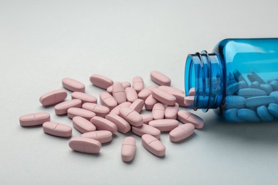 Photo of Vitamin pills and bottle on grey background, closeup