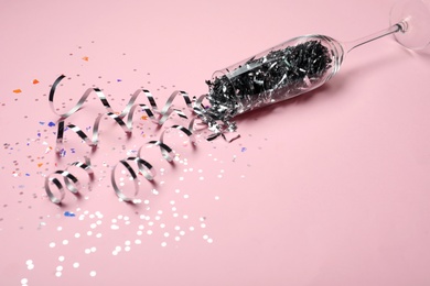 Photo of Glass and shiny confetti on pink background