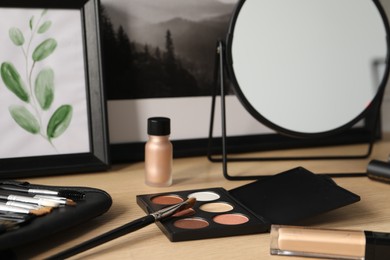 Photo of Mirror and makeup products on wooden dressing table, closeup