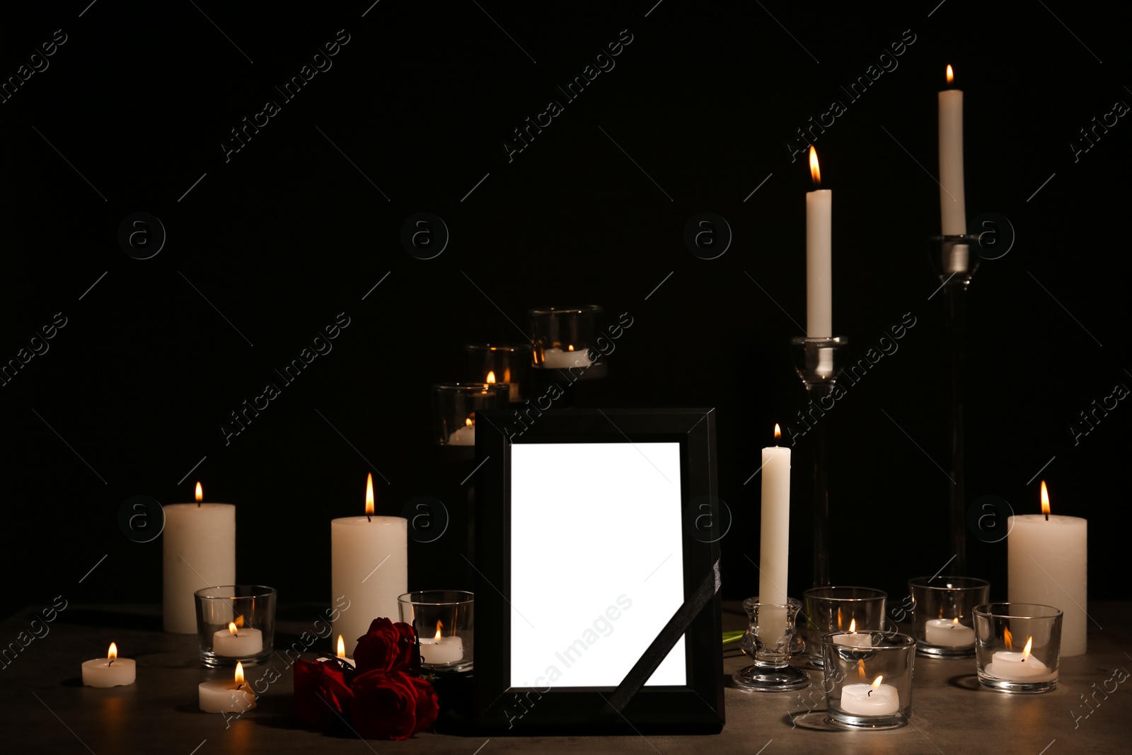 Photo of Empty frame with black ribbon, candles and roses on table. Funeral symbol