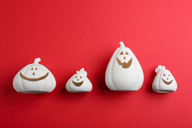 White pumpkin shaped candle holders on red background, flat lay. Halloween decoration