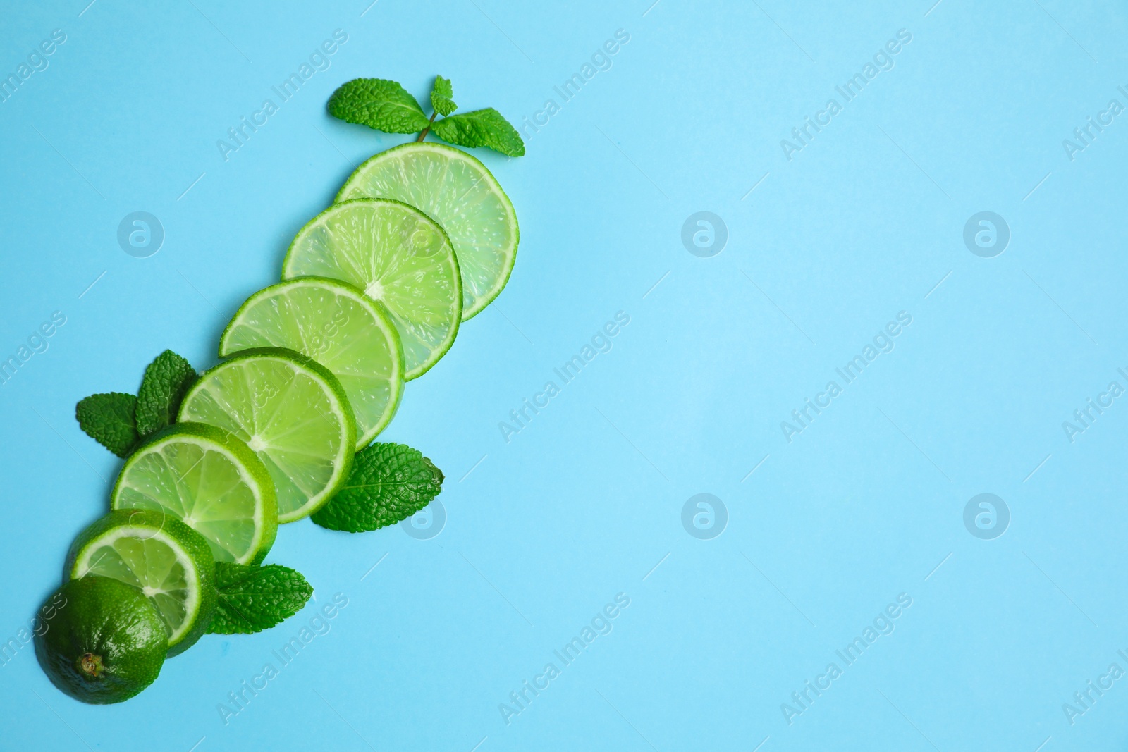 Photo of Slices of fresh juicy lime and mint on blue background, flat lay. Space for text