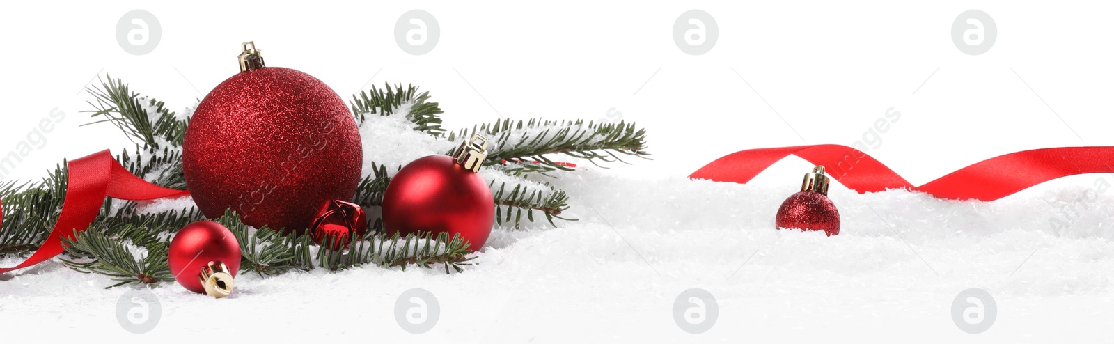 Photo of Beautiful red Christmas balls, fir tree branch and ribbon on snow against white background