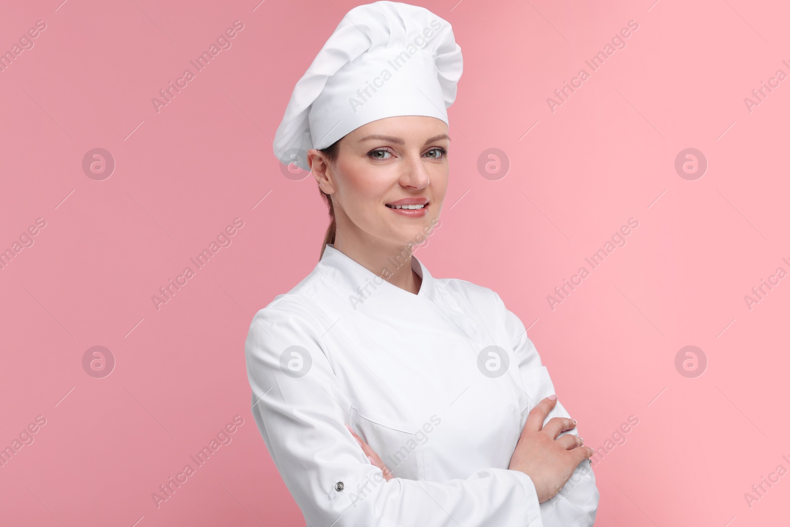 Photo of Happy woman chef in uniform on pink background