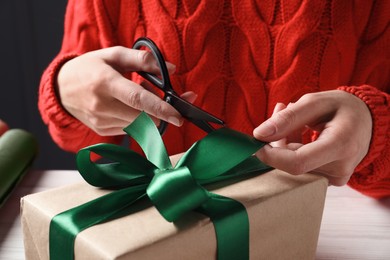 Photo of Christmas present. Woman decorating gift box at table, closeup