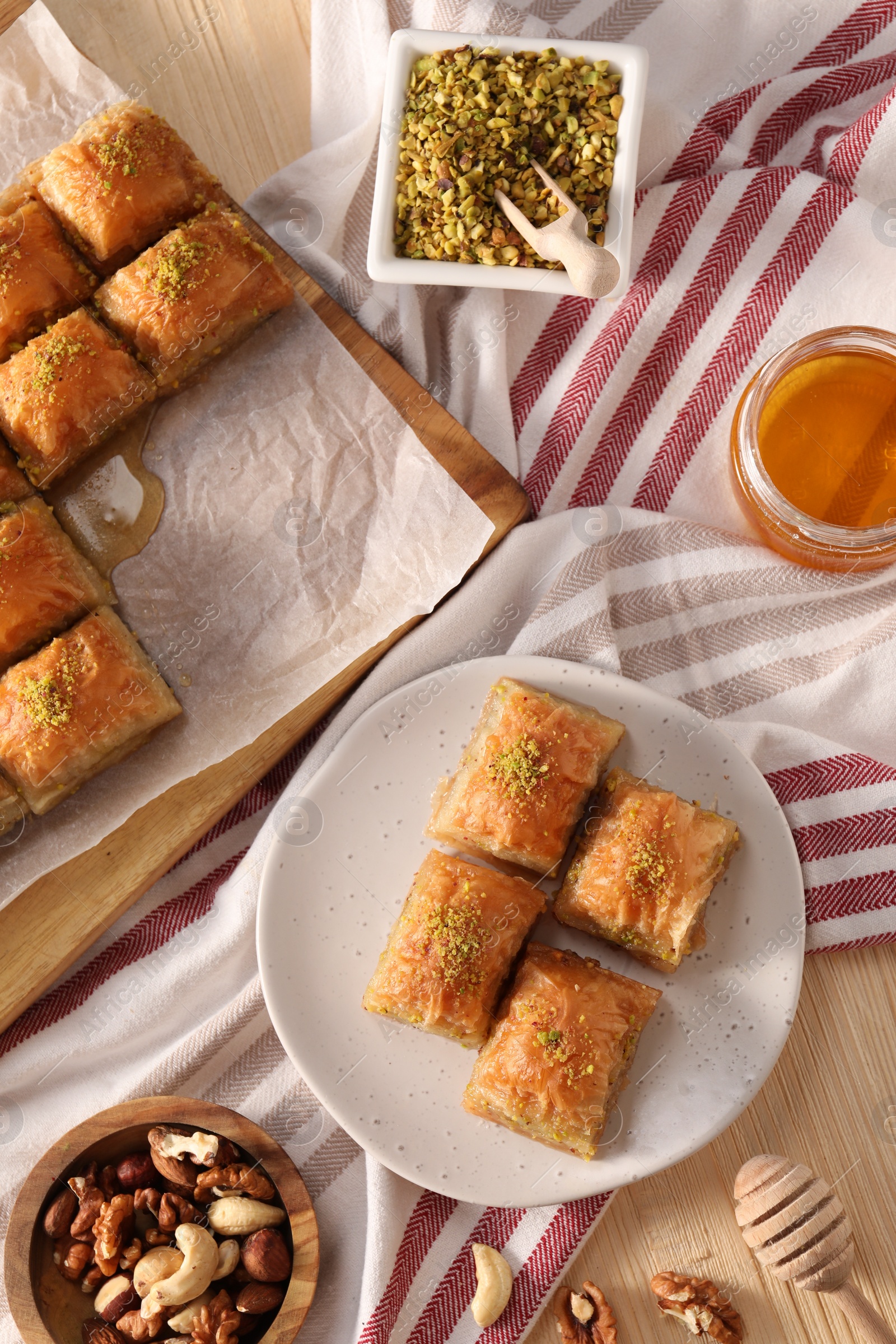 Photo of Delicious sweet baklava with nuts and honey on table, flat lay