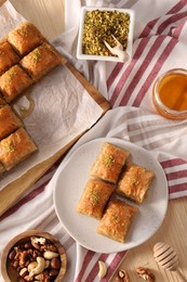 Photo of Delicious sweet baklava with nuts and honey on table, flat lay