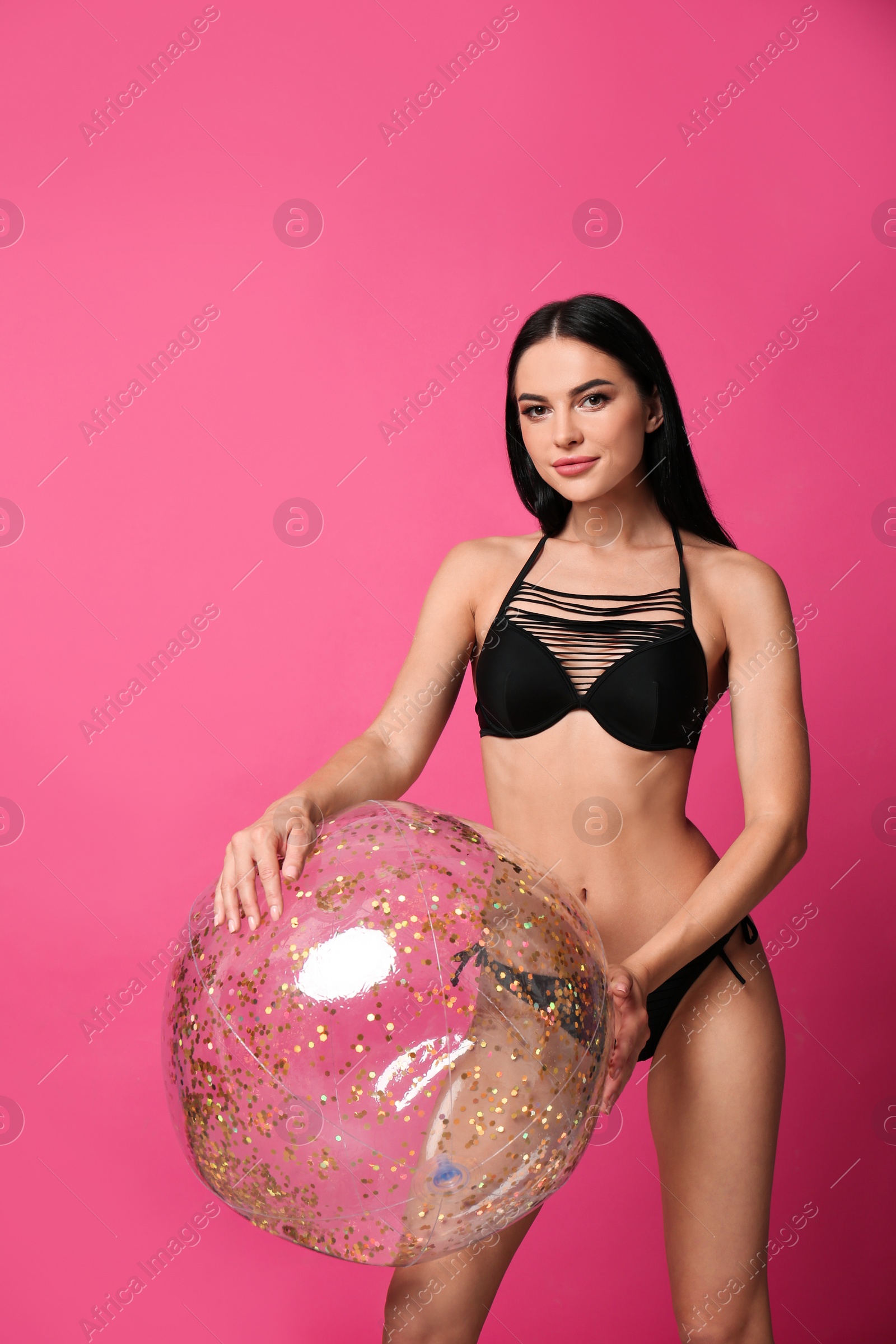 Photo of Beautiful young woman in stylish bikini with beach ball on pink background