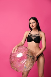 Photo of Beautiful young woman in stylish bikini with beach ball on pink background