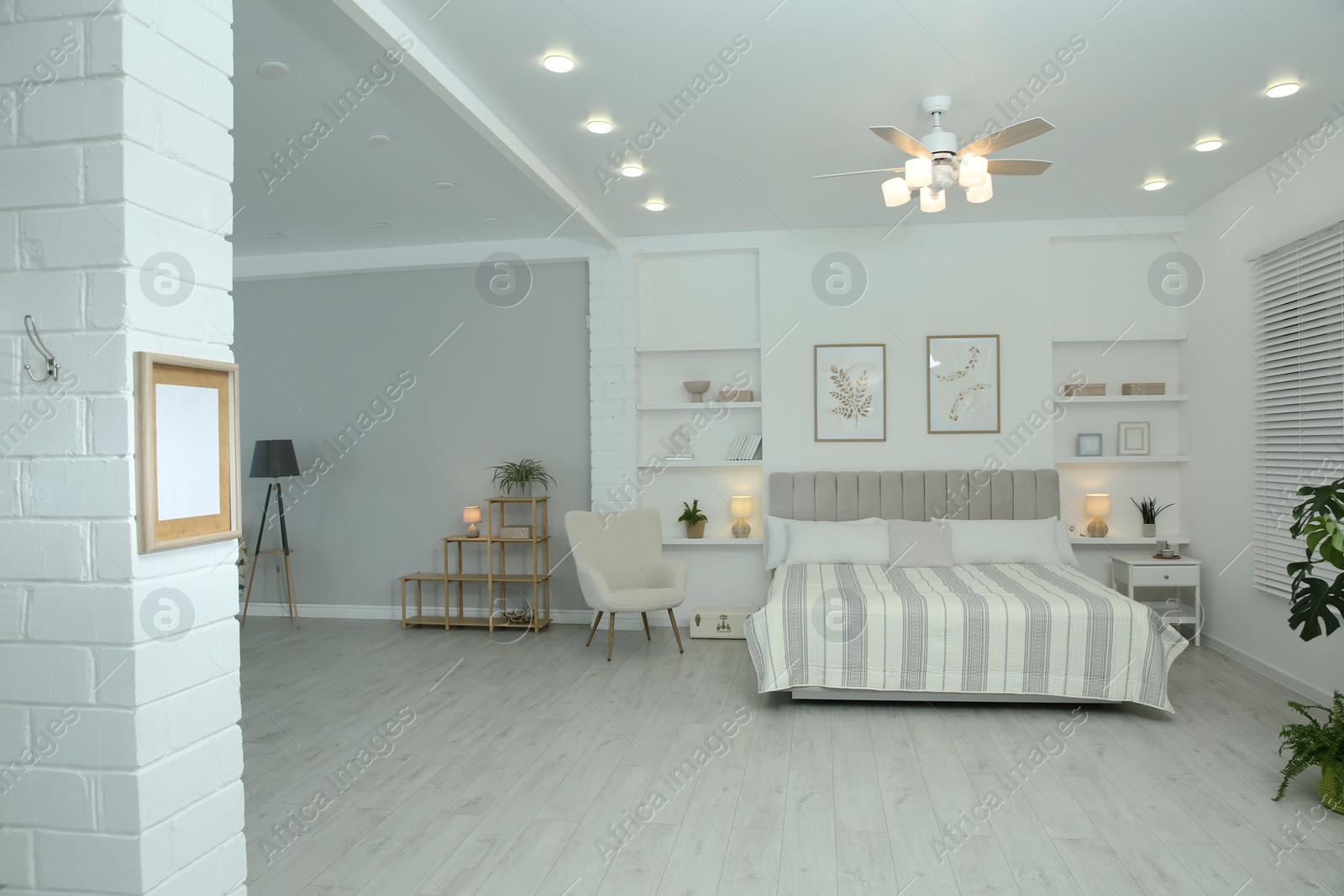 Photo of Comfortable furniture, ceiling fan, houseplants and accessories in stylish bedroom