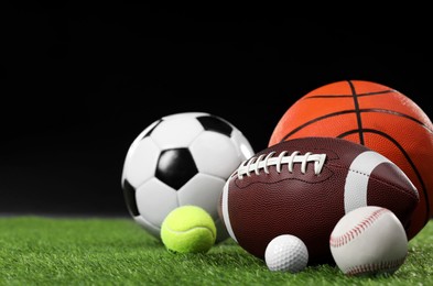 Many different sports balls on green grass against black background, space for text