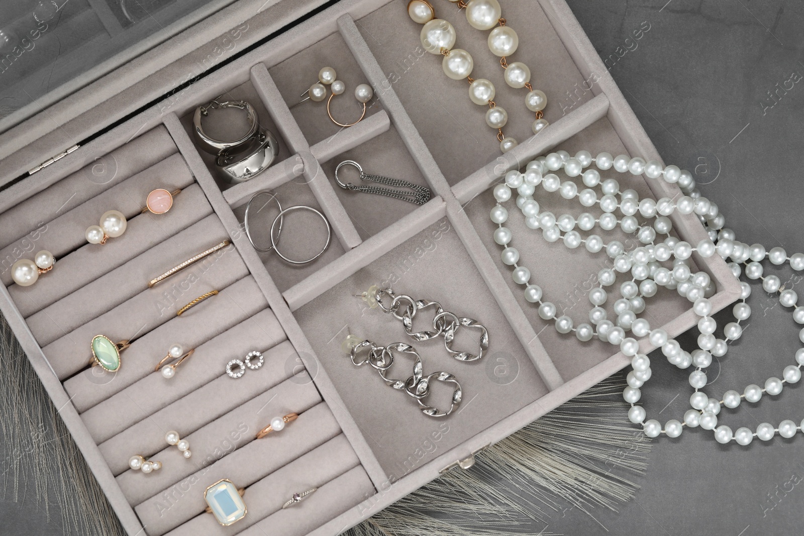 Photo of Jewelry box with many different accessories on grey table, top view