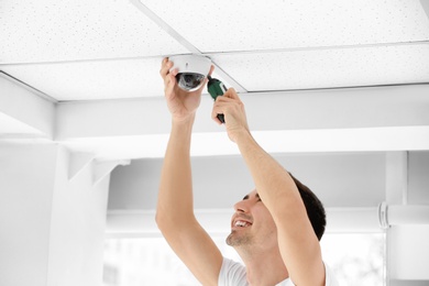 Photo of Technician installing CCTV camera on ceiling indoors