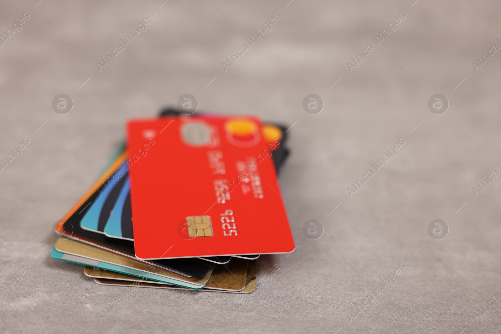 Photo of Pile of different credit cards on grey table, closeup. Space for text