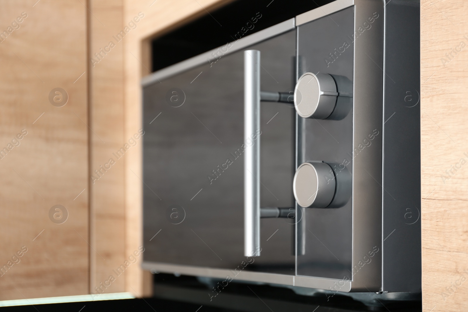 Photo of Modern microwave oven on shelf in kitchen