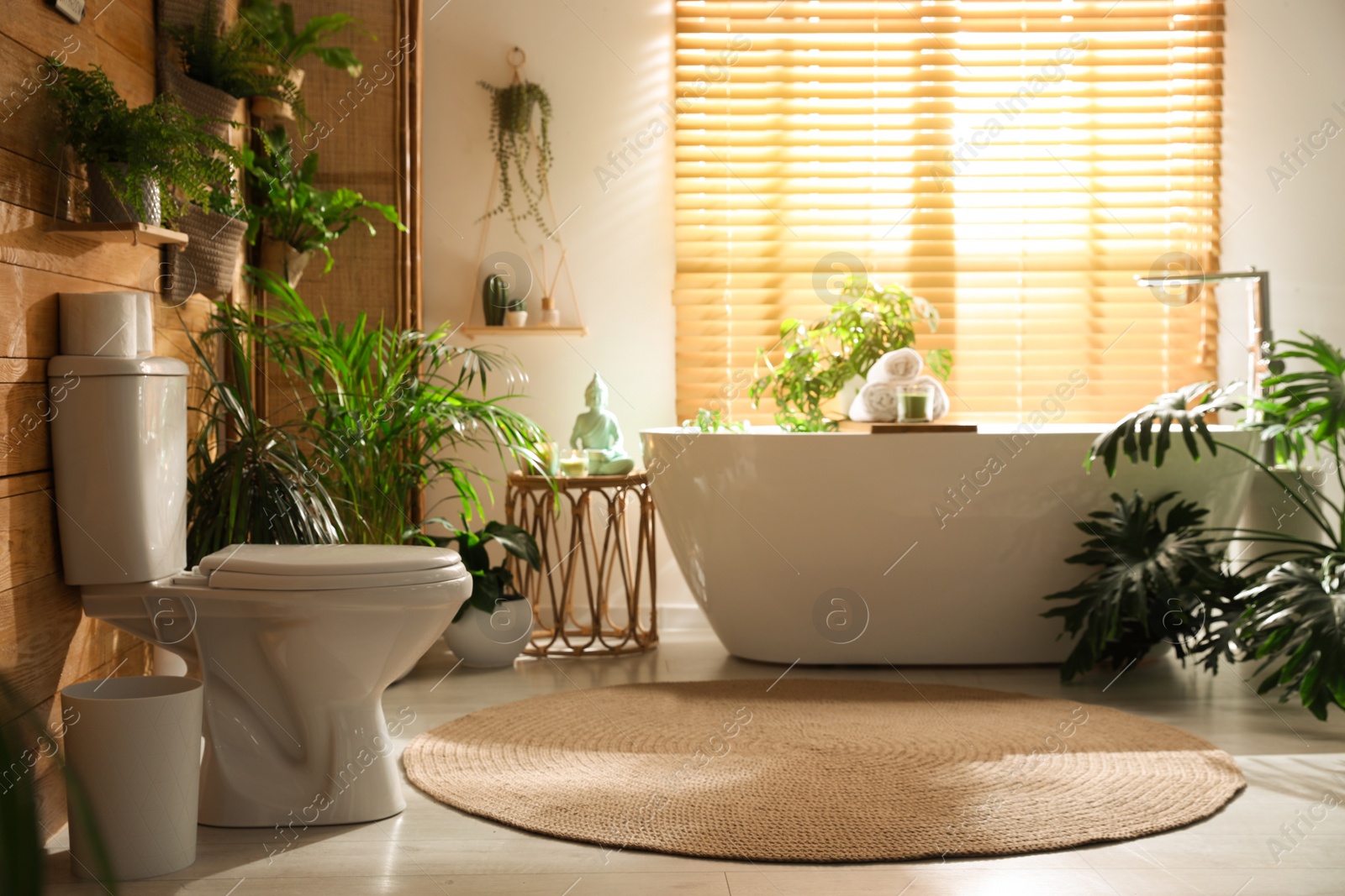 Photo of Stylish bathroom interior with toilet bowl and green plants