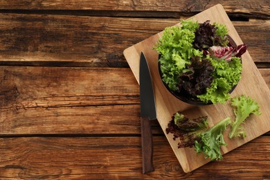 Different sorts of lettuce and knife on wooden table, flat lay. Space for text