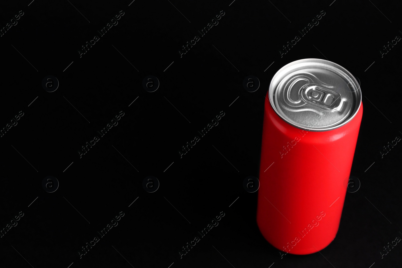 Photo of Energy drink in red can on black background, space for text