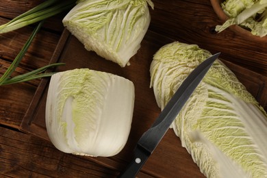 Photo of Whole and cut fresh Chinese cabbages on wooden table, flat lay