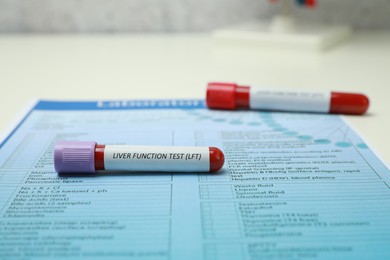 Liver Function Test. Tubes with blood samples and form on table, closeup