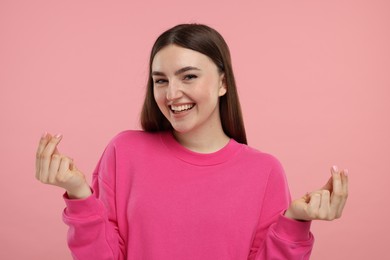 Photo of Happy woman showing money gesture on pink background