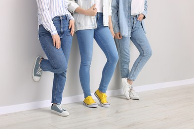 Photo of Women in stylish jeans near light grey wall indoors, closeup