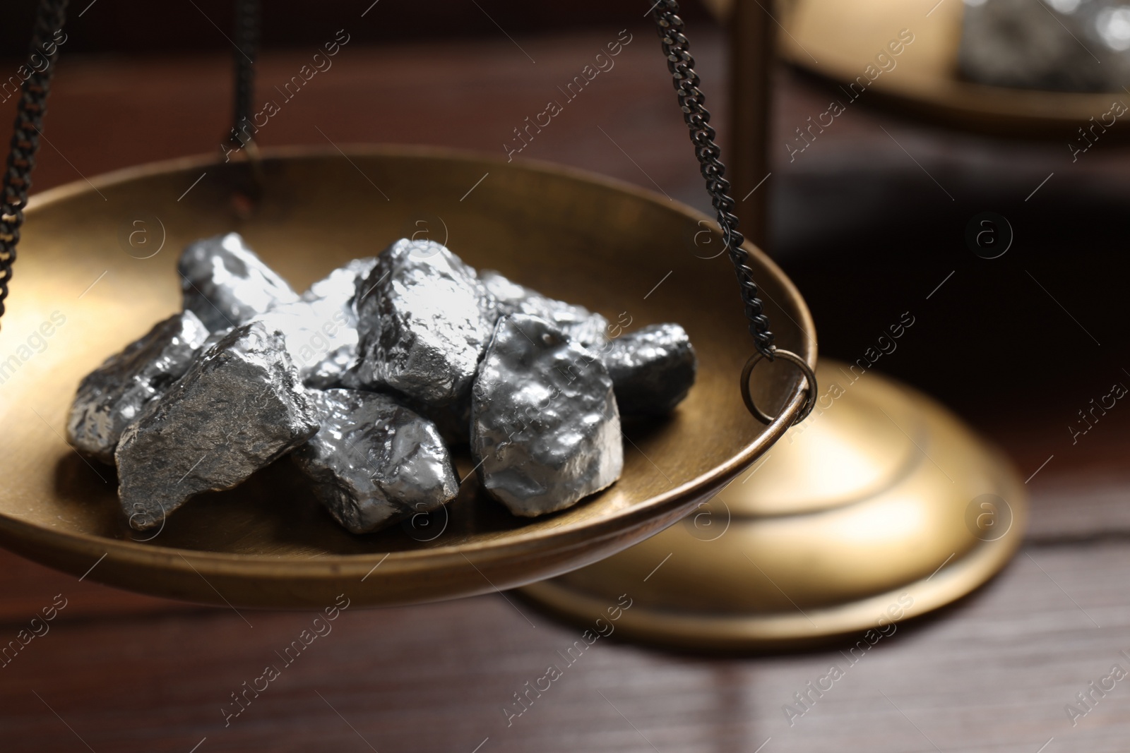 Photo of Vintage scales with silver nuggets on wooden table, closeup