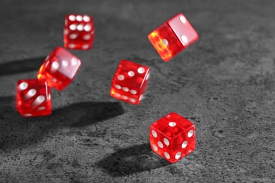 Photo of Many red game dices falling on grey textured table. Space for text