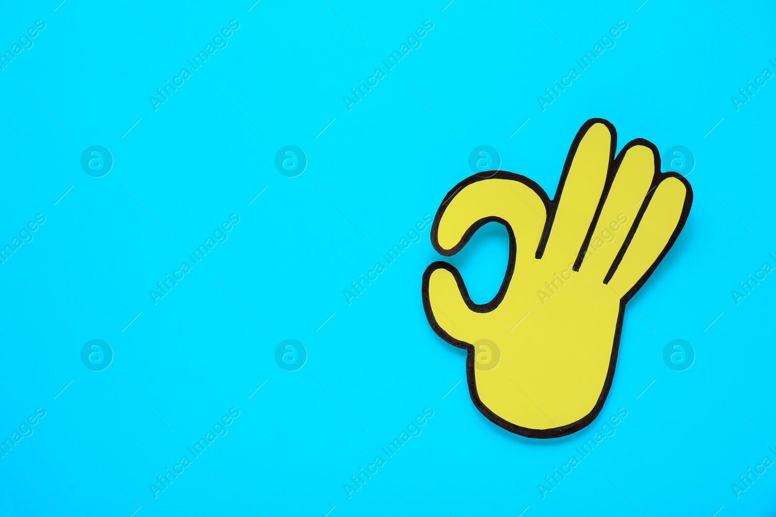 Photo of Paper cutout of okay hand gesture on light blue background, top view. Space for text