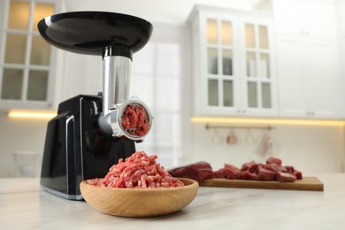 Photo of Electric meat grinder with minced beef on white marble table in kitchen. Space for text