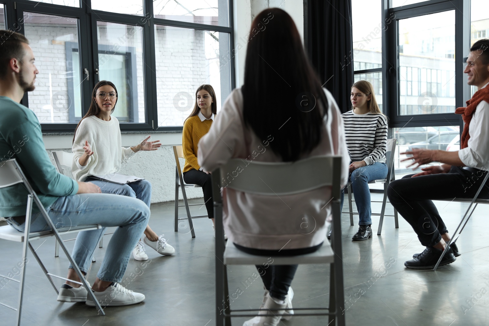 Photo of Psychotherapist working with patients in group therapy session indoors