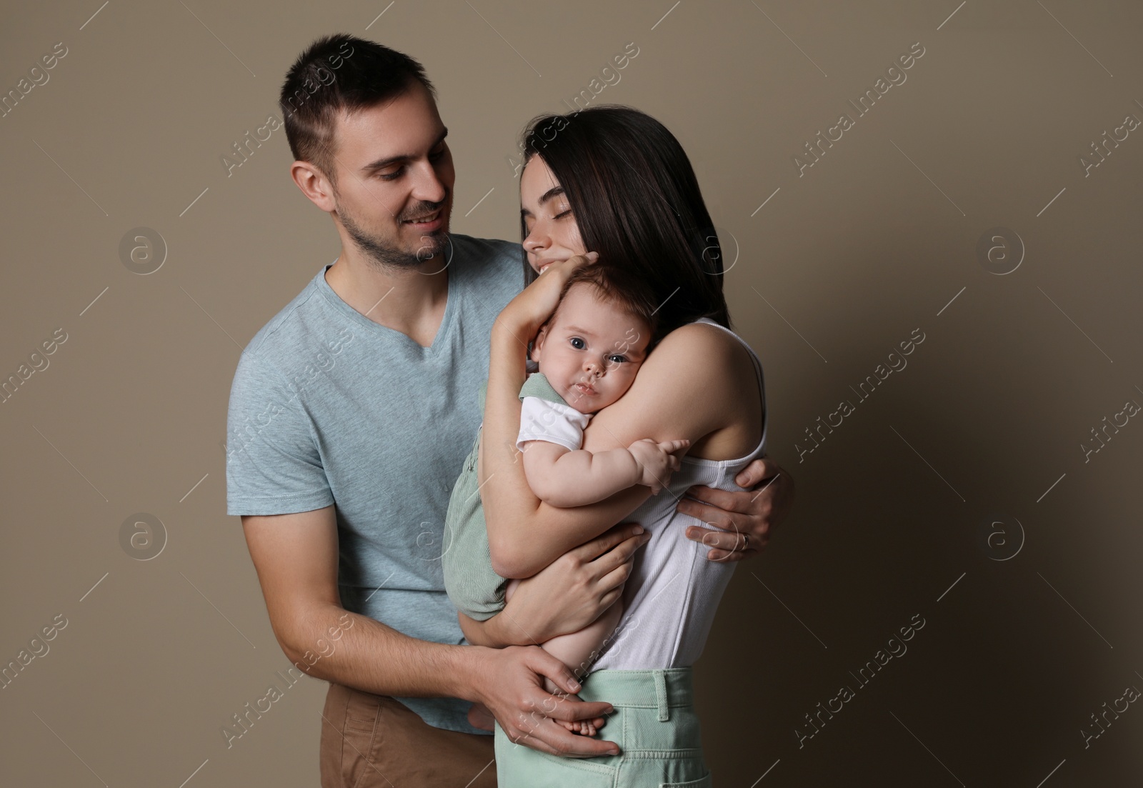 Photo of Happy family. Couple with their cute baby on beige background