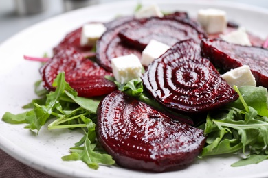 Photo of Roasted beetroot slices with feta cheese and arugula on plate, closeup