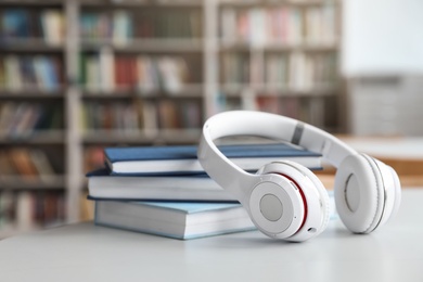 Photo of Stack of books and headphones on table in library