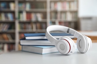 Stack of books and headphones on table in library