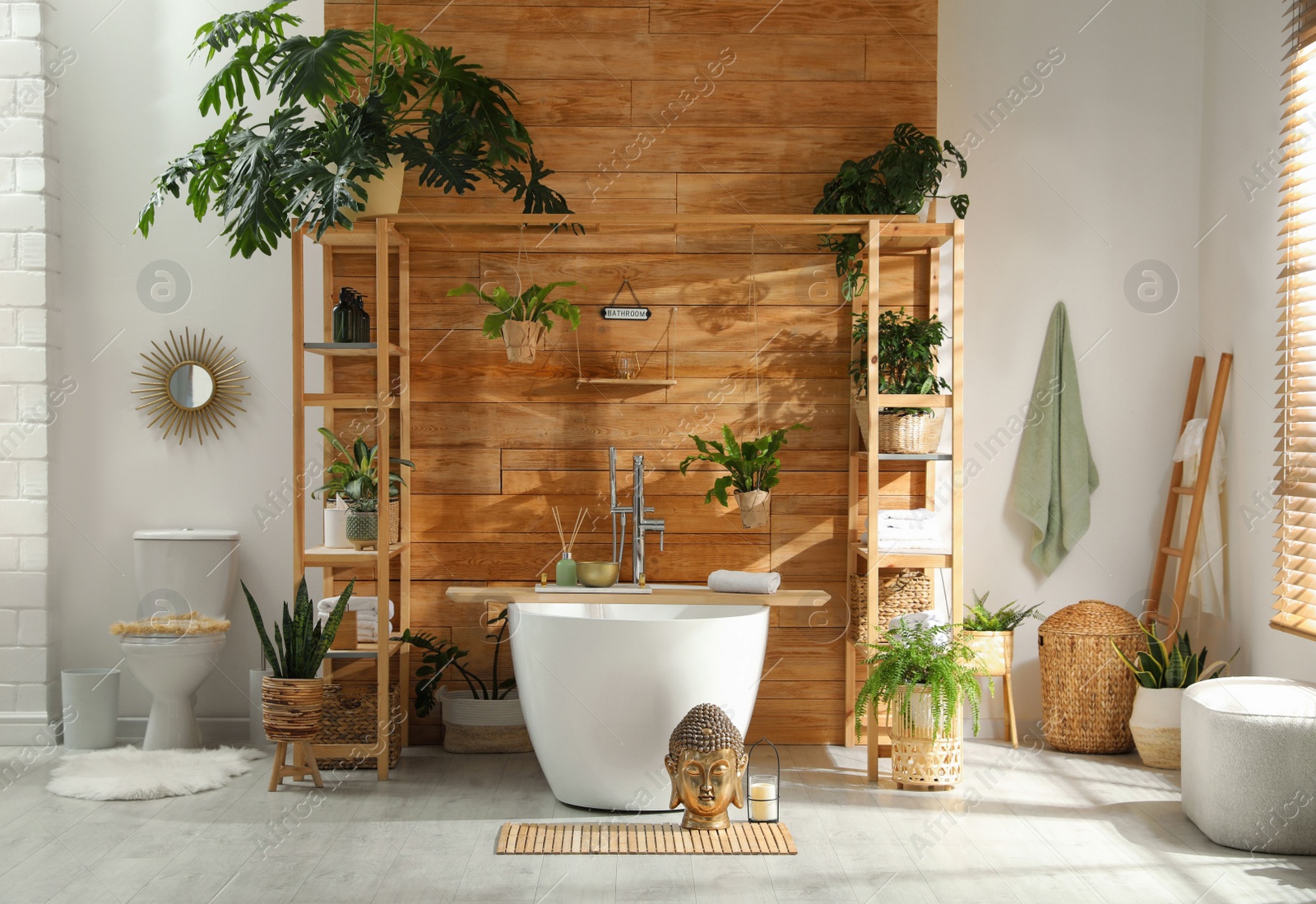 Photo of Stylish bathroom interior with white tub and green houseplants near wooden wall. Idea for design