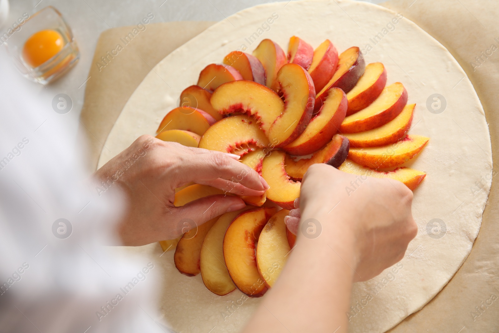 Photo of Woman making peach pie at table, closeup