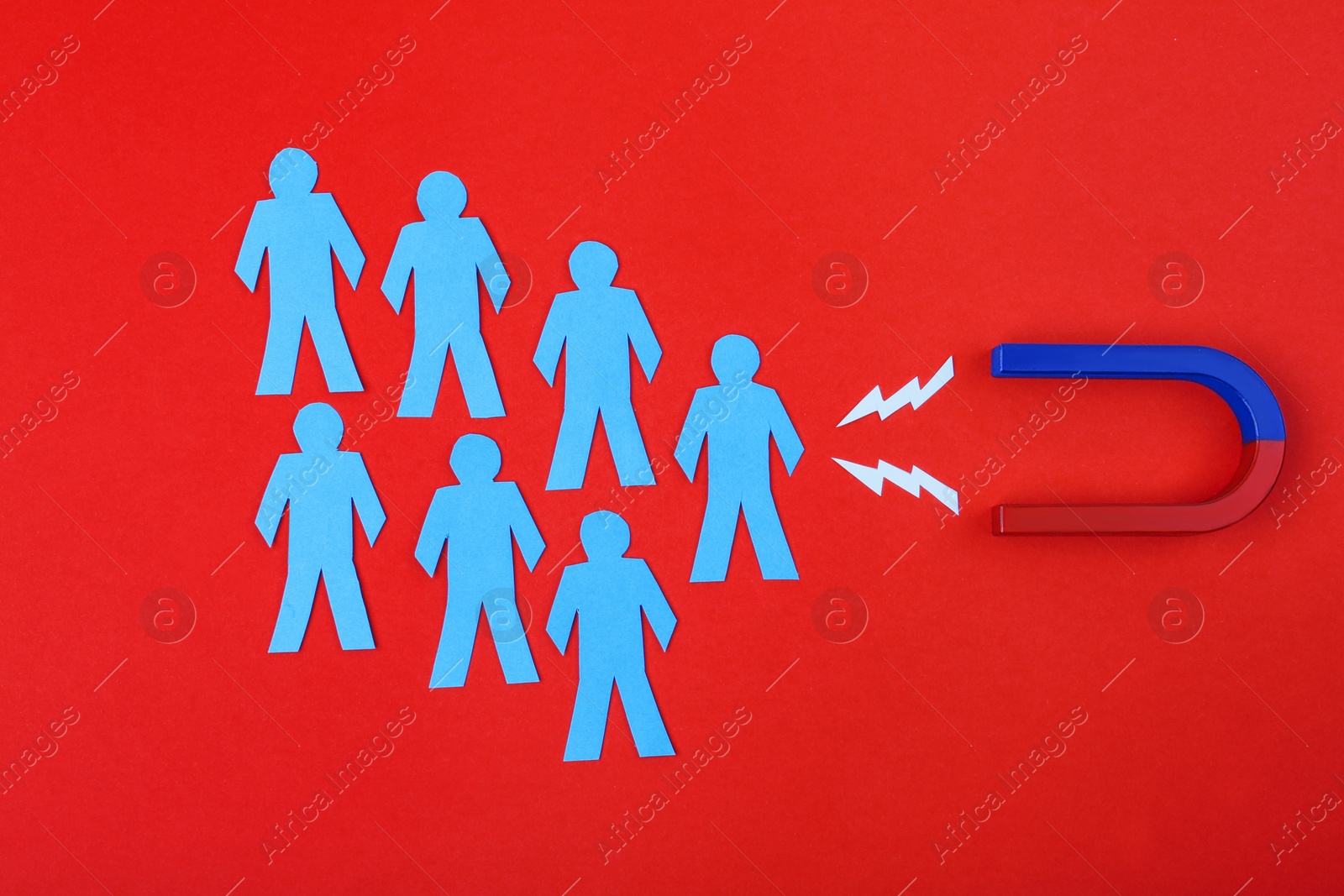 Photo of Magnet and paper people on crimson background, flat lay