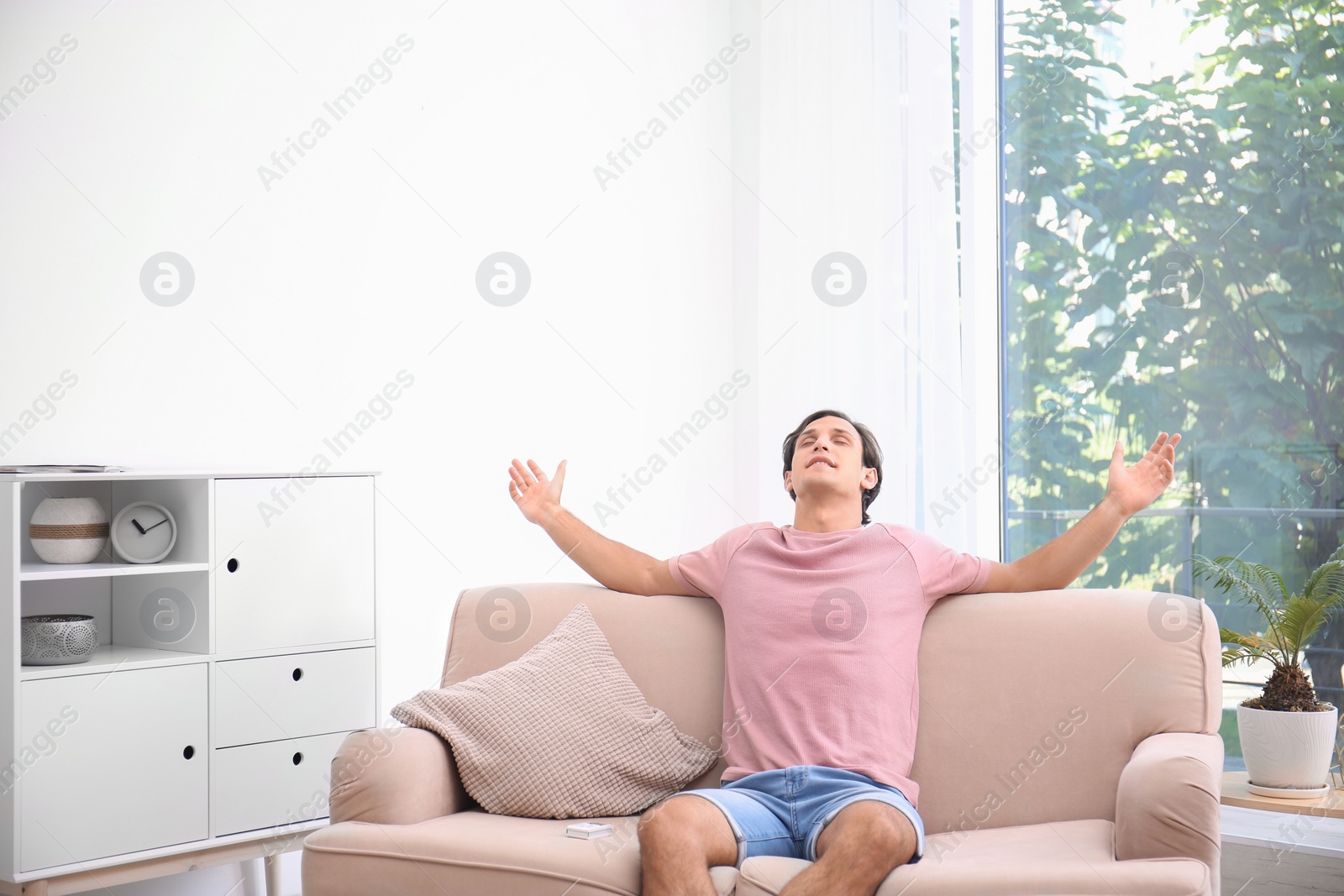 Photo of Young man relaxing under air conditioner at home