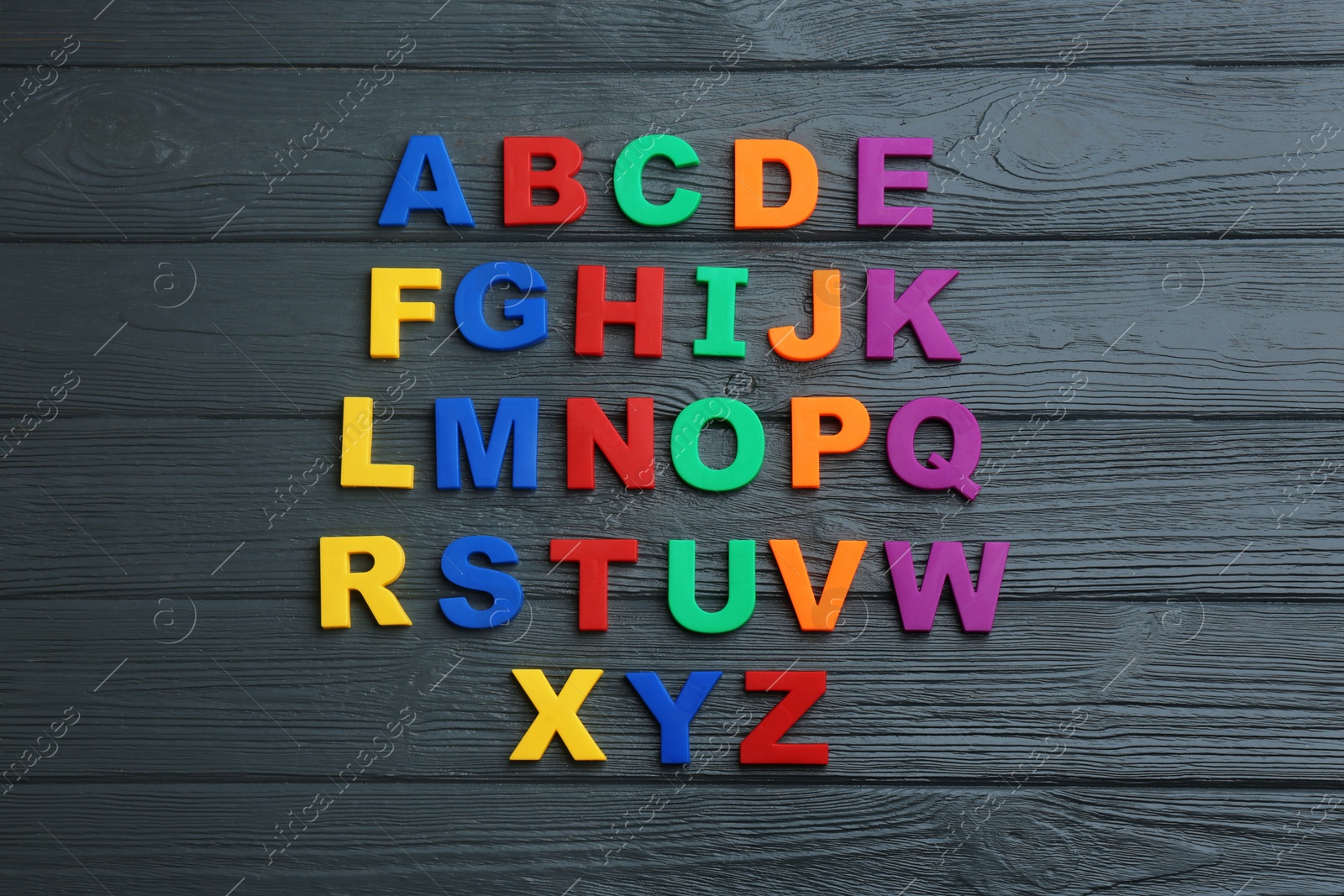 Photo of Colorful magnetic letters on black wooden background, flat lay. Alphabetical order