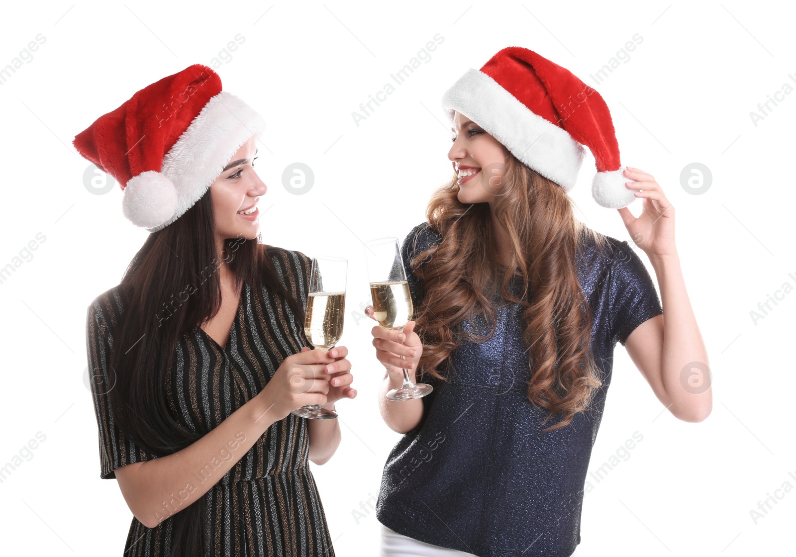 Photo of Beautiful young women in Santa hats with glasses of champagne on white background. Christmas celebration