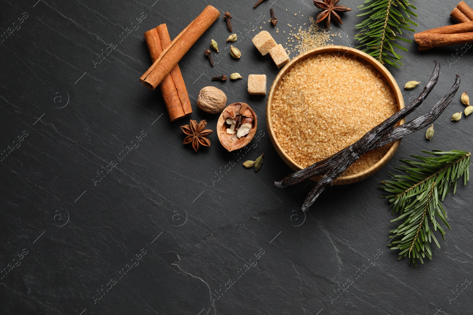 Photo of Different aromatic spices and fir branches on dark textured table, flat lay. Space for text